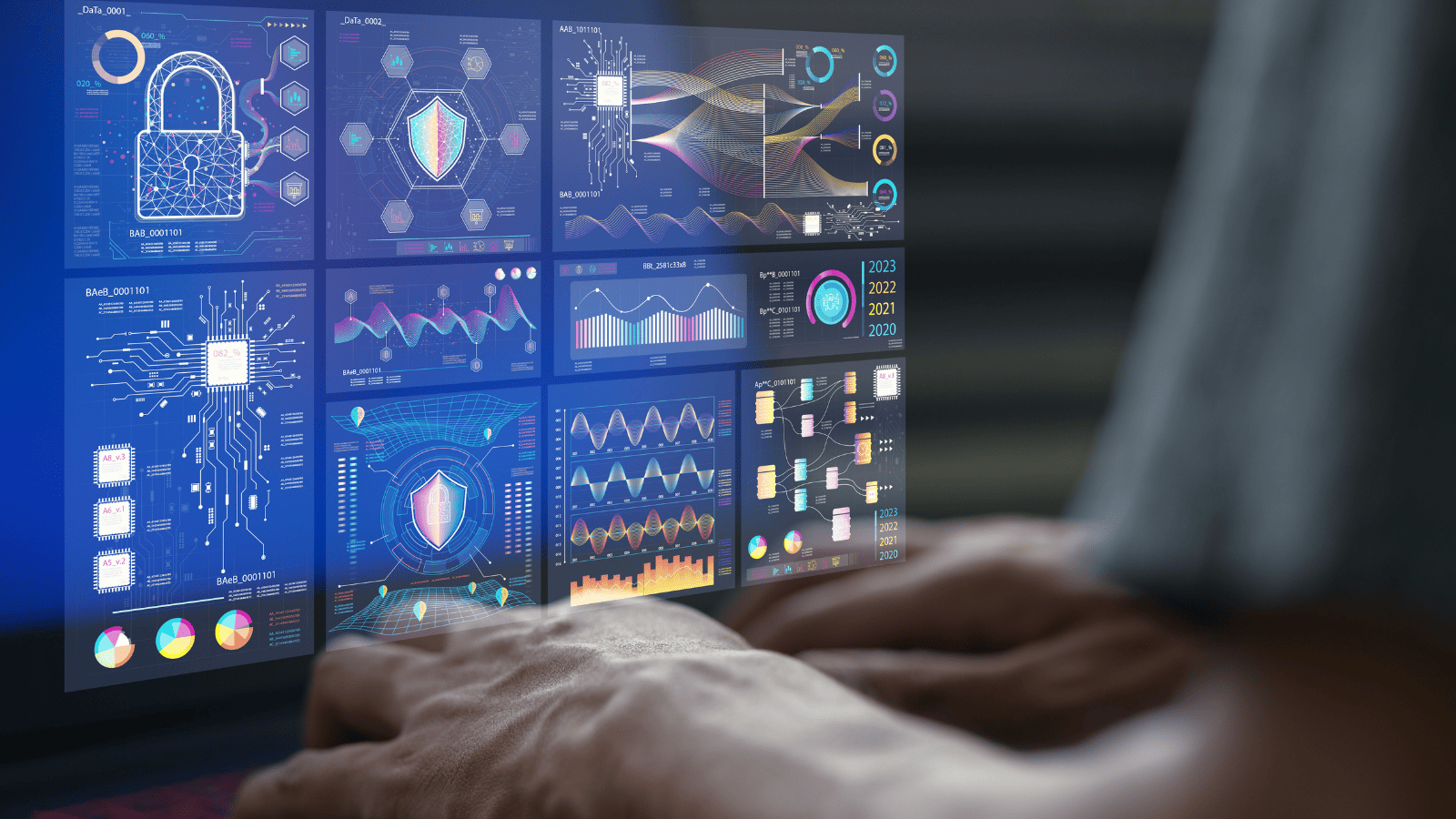 Pessoa usando um computador com dashboards digitais de segurança, dados e inteligência artificial na tela, exibindo gráficos, circuitos, ícones de cadeado e painéis tecnológicos em uma interface futurista.